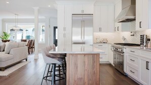 Una cocina moderna con armarios blancos, electrodomésticos de acero inoxidable y una isla central con taburetes de bar.