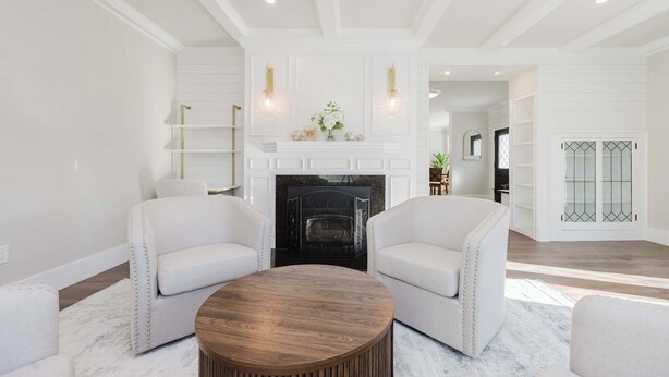 Una sala de estar moderna con chimenea, sofás blancos y una mesa de centro redonda.