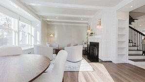 Una sala de estar moderna con comedor, chimenea y escalera.
