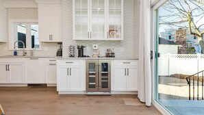 Una cocina moderna con armarios blancos, un refrigerador de acero inoxidable y un ventanal con vistas al exterior.