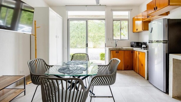 A modern kitchen with a dining area, large windows, and a ceiling fan. - Cozy private studio apartment in Jaco with refreshing AC for your stay (Jaco)