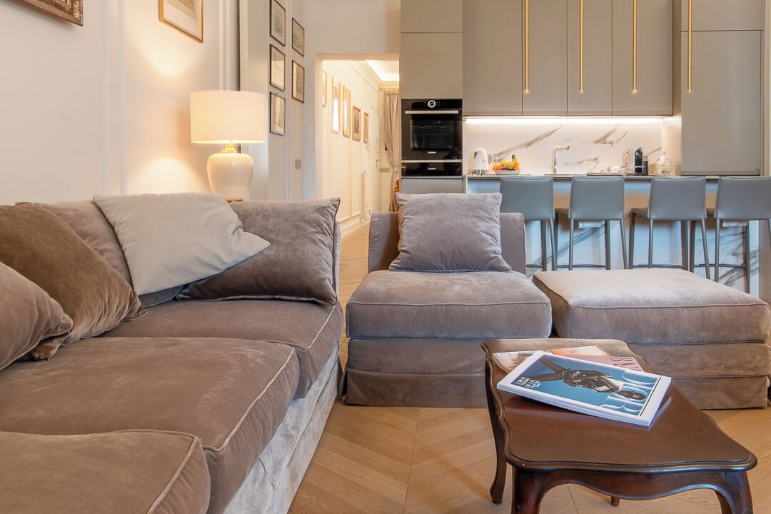 A modern living room with a sofa, ottoman, and a coffee table with a magazine.