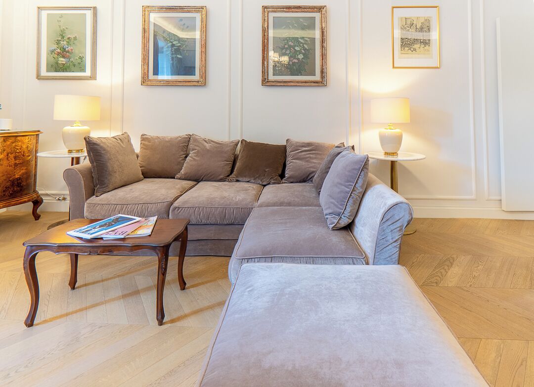 A living room with a sectional sofa, a coffee table, and two wall-mounted lamps.