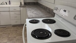 A kitchen with white cabinets, a stove, and a countertop.