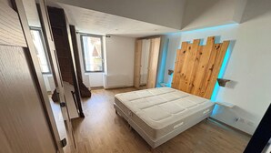 Ein Schlafzimmer mit Holzboden, einem Bett, einem Fenster und einer Holzwandverkleidung.