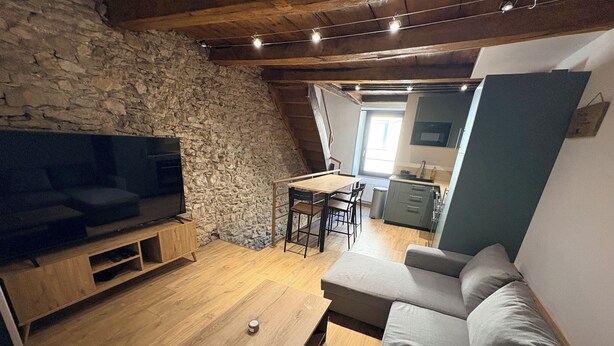 Ein gemütliches Wohnzimmer mit Steinwand, Holzmöbeln, einem Fernseher und einem Essbereich.