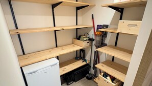 Ein kleiner Stauraum mit Holzböden und einem weißen Gerät, vermutlich einer Minikühlschrank, auf der linken Seite.