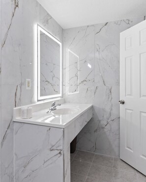 A bathroom with marble walls, a white sink, and a door.