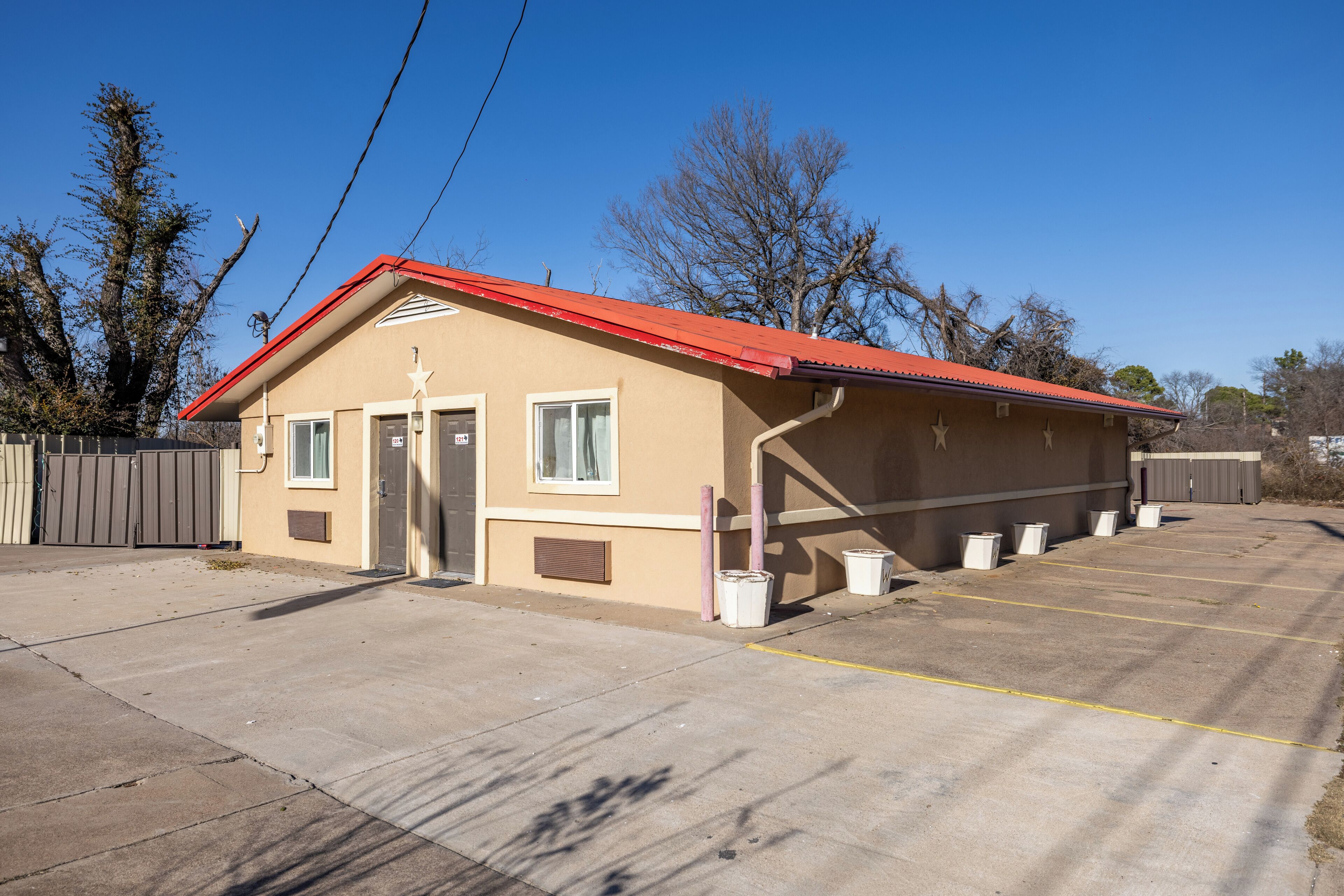 A single-story building with a red roof, a small porch, and a parking lot with marked spaces.