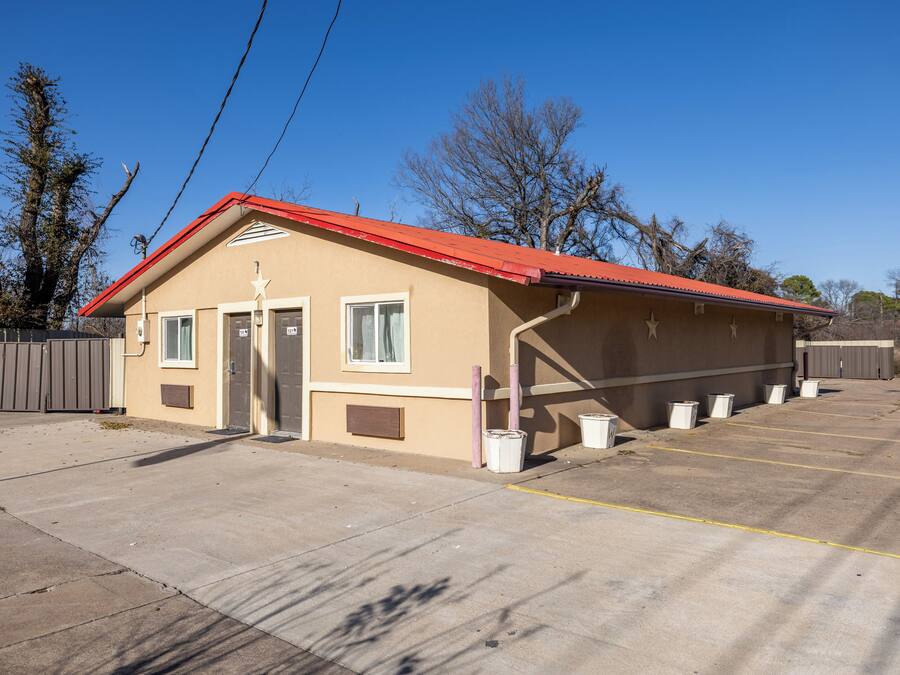 A single-story building with a red roof, a small porch, and a parking lot with marked spaces.
