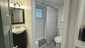 Une salle de bain avec un lavabo blanc, un miroir et un rideau de douche.