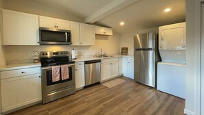 A modern kitchen with white cabinets, stainless steel appliances, and a wooden floor. - 4 Bedrooms ~ Clean & Comfortable! (Plattsburgh)