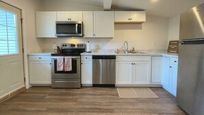 Une cuisine moderne avec des armoires blanches, des appareils en acier inoxydable et un plancher en bois.