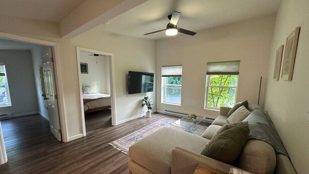 Un salon spacieux avec un grand canapé, un téléviseur à écran plat et un ventilateur de plafond.