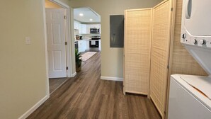 Un cuarto de lavandería con lavadora, secadora y una puerta que da a una cocina.