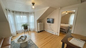 Una sala de estar moderna con piso de madera, un sofá, una mesa de centro, un radiador y un televisor montado en la pared.