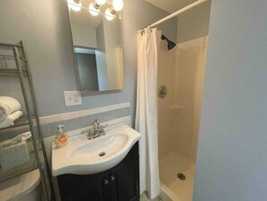 A bathroom with a sink, mirror, and shower.