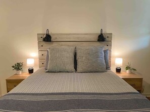 A bed with a headboard, two bedside tables, and lamps.