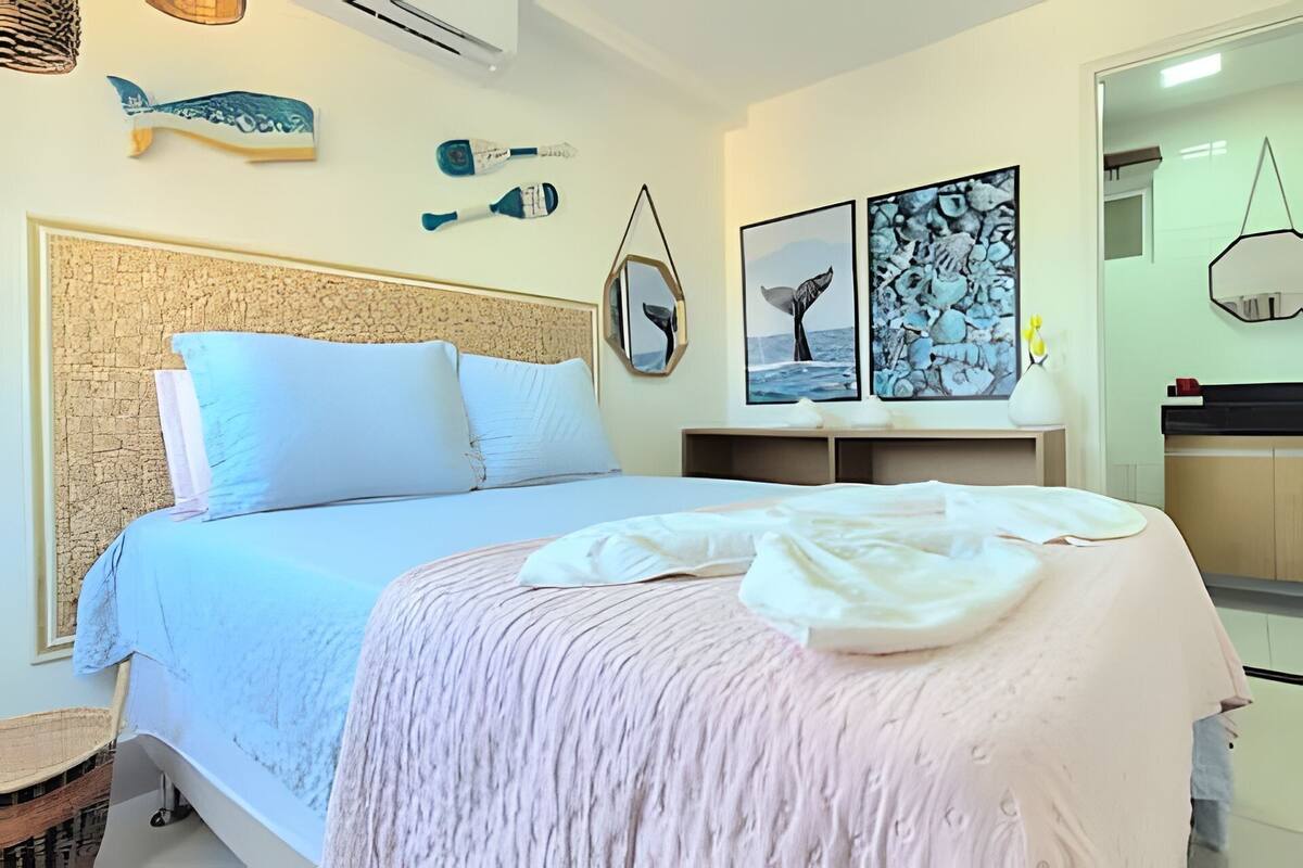 Une chambre à coucher avec un grand lit, une tête de lit et des œuvres d’art murales comprenant des illustrations de poissons et de baleines.
