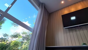 A room with a large window, a flat-screen TV mounted on the wall, and a ceiling with recessed lighting. - Aline Duque by Temporada Inn (Ipojuca)