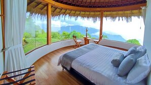 A bedroom with a curved ceiling, a bed with pillows, a small table, and chairs. - Minca El Dorado Reserve (Minca)
