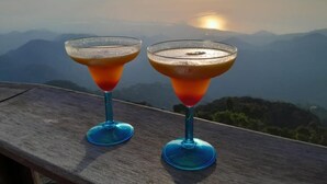 Two cocktails on a wooden table with a mountain view in the background. - Minca El Dorado Reserve (Minca)
