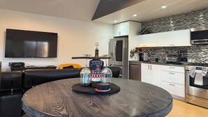 A modern kitchen with a built-in oven, a refrigerator, and a microwave. There is a dining table with a decorative centerpiece.