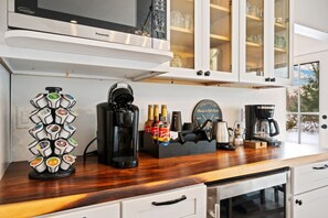 A kitchen with a coffee maker, a coffee grinder, and a coffee pod holder on the counter. - Egg Harbor New Home on Golf Course w/ Game Room (Egg Harbor)