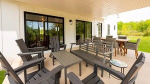 Un patio al aire libre con mesa y sillas, una pequeña mesa redonda y vistas a un paisaje verde.
