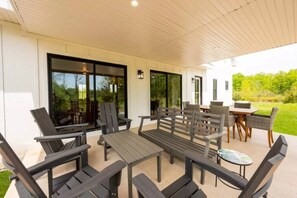 Eine Terrasse im Freien mit Tisch und Stühlen, einem kleinen runden Tisch und Blick auf eine grüne Landschaft.