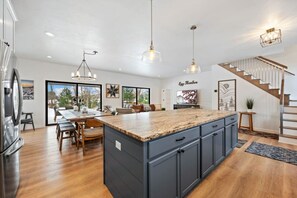 Eine moderne Küche mit Granit Arbeitsplatten, dunklen Schränken und Pendelleuchten.