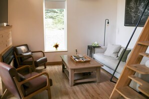 A living room with a sofa, chairs, a coffee table, a window with a view, and a wall-mounted light fixture. - Scandi Cabin•Hot Tub• 4 Electric Fireplaces• (Franklin Township)