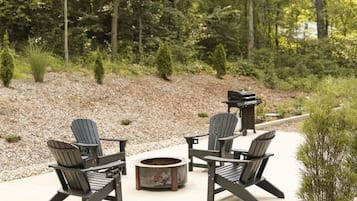 An outdoor seating area with Adirondack chairs and a fire pit.