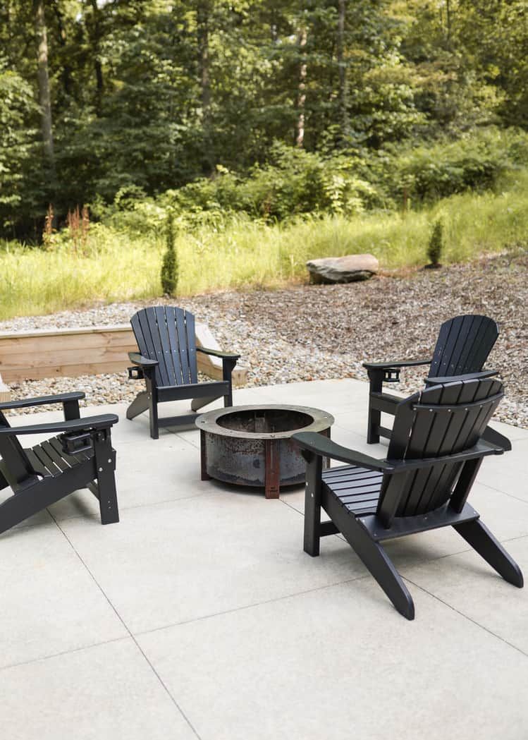 En uteplats med Adirondack-stolar och en eldstad.