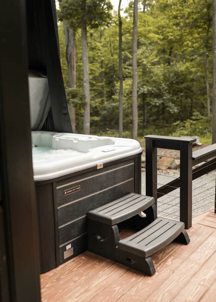 Un bain à remous doté d’une terrasse en bois et d’une rambarde en métal.