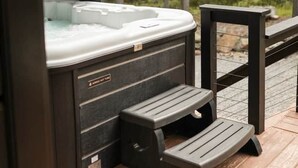 Uma banheira de hidromassagem com deck de madeira e guarda-corpo de metal.