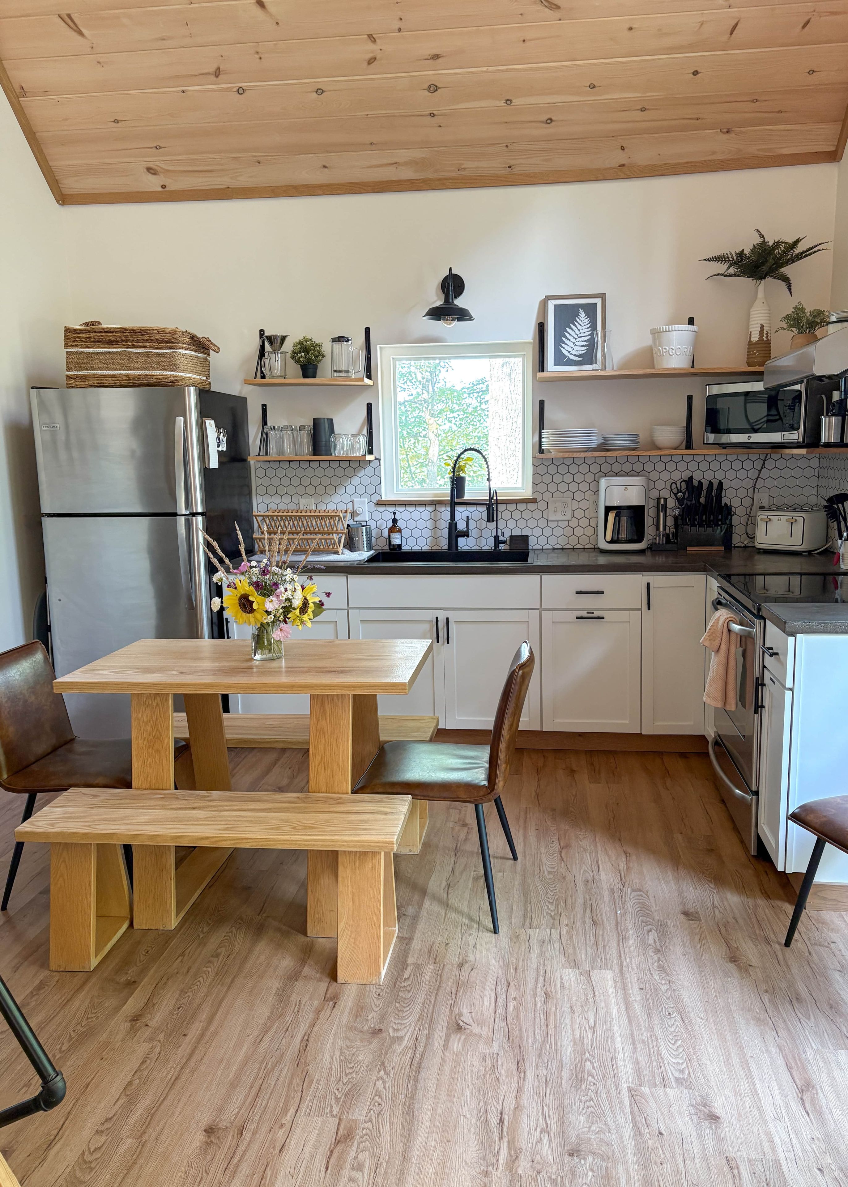 Une cuisine moderne avec une table en bois, des chaises, un réfrigérateur, un four à micro-ondes et un évier.