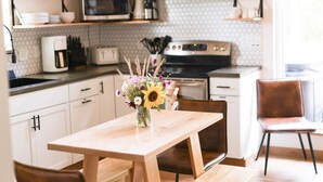 A kitchen with white cabinets, a wooden table, and a vase of flowers.