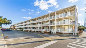 A multi-story motel with balconies and a parking lot. - Treasure’s Cove at Seaway | Steps to the Beach (Ocean City)