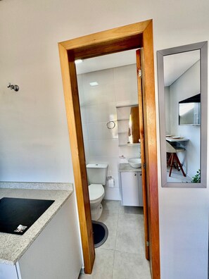 A compact bathroom with a toilet, sink, and mirror. - Estudio Campeche (Florianópolis)