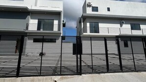 Un bâtiment moderne composé de structures à deux étages, doté d’une clôture en métal et surplombant un ciel dégagé.