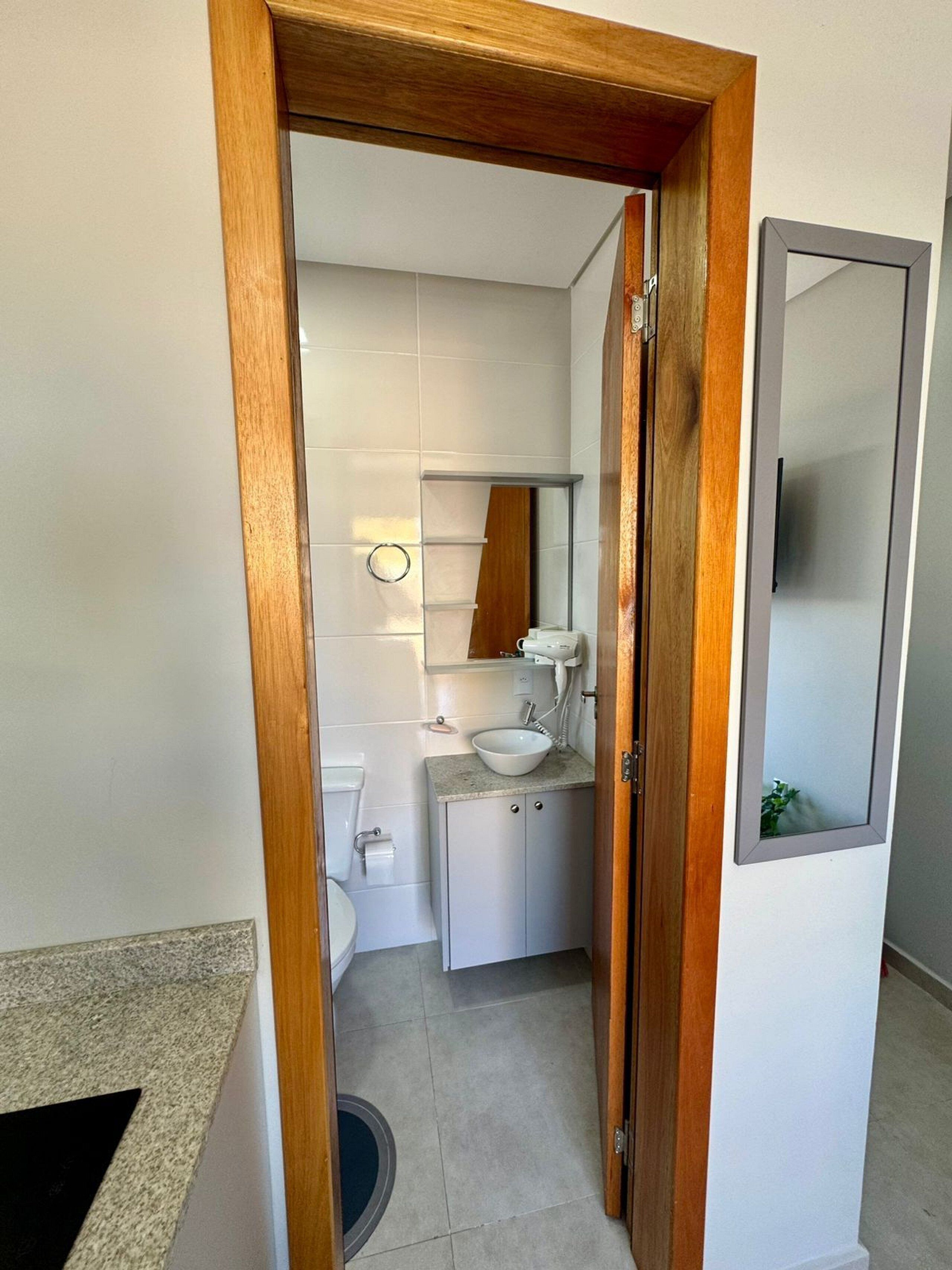 Et lille badeværelse med toilet, vask og spejl.