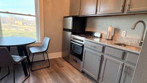 A modern kitchen with a dining area, stainless steel appliances, and a view of the outdoors. - Experience Sherman Hill from the Olive 3, 1 bed apartment in downtown Des Moines (Des Moines)