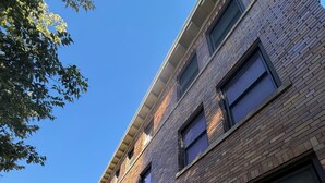 A multi-story brick building with large windows and a visible garage door. - Experience Sherman Hill from the Olive 3, 1 bed apartment in downtown Des Moines (Des Moines)