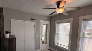 A bedroom with a bed, a ceiling fan, a window with blinds, and a door. - Experience Sherman Hill from the Olive 3, 1 bed apartment in downtown Des Moines (Des Moines)