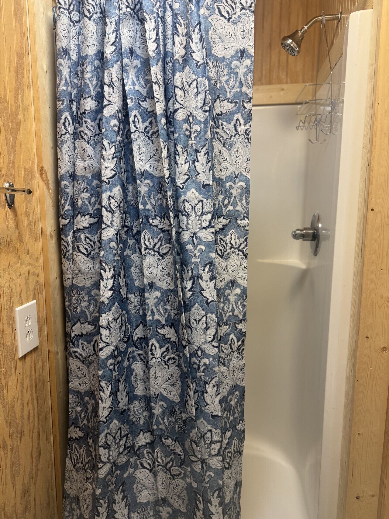 Un baño con ducha, puerta de madera y barra para toallas.