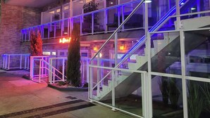 Un hôtel à plusieurs étages, doté de balustrades en verre et d’un éclairage bleu sur sa façade.