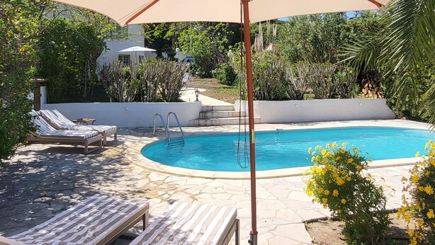 Ein Poolbereich mit Liegestühlen und einem großen Sonnenschirm.