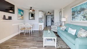 A living room with a teal sofa, white chairs, a coffee table, and artwork on the walls. - Wake Up to Waves | Stunning Oceanfront Condo (North Myrtle Beach)