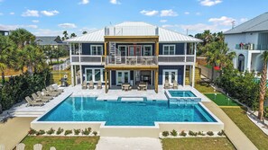 A two-story house with a large swimming pool, outdoor seating, and a covered patio area. - New Beach Listing! Harmony Key - 8BR, 5Bath, Private Beach, Pool, Spa! (Pensacola)